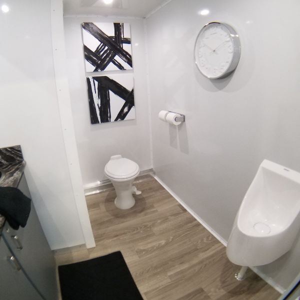Private restroom trailer room with a flushing toilet and wall art